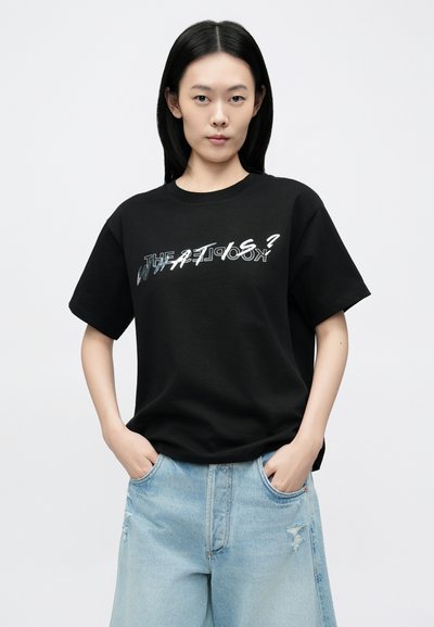 T-shirt preta de algodão com um design gráfico de texto em prata e branco, complementada por calções de ganga azul-clara com um corte descontraído e bolsos.