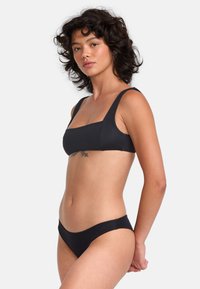 Black bikini set featuring a square-neck bralette with wide straps and low-rise bottoms. Smooth, stretchy fabric with a minimalist design.