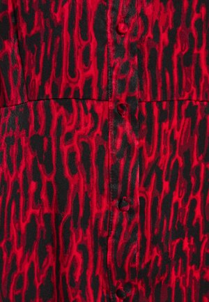 Rot-schwarz gemusteter Stoff mit abstraktem Design, mit Knöpfen vorne und einer glatten, glänzenden Textur.