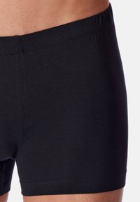Schwarze Baumwoll-Boxershorts mit elastischem Bund, die über eine glatte Textur und ein tailliertes Design verfügen. Keine sichtbaren Logos oder Muster.
