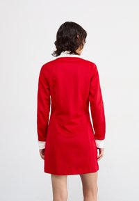 Rode jurk met lange mouwen, een witte kraag en een getailleerde uitstraling. Gladde textuur, knie-lengte en op maat gemaakte naden voor een gestructureerd uiterlijk.