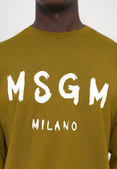 Õlivärvi pikkade varrukatega särk, mille esiküljel on suur valge harja tekst "MSGM MILANO", valmistatud pehmest ja tekstuuriga kangast.