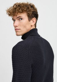 Maglione girocollo lavorato a maglia di colore blu navy, caratterizzato da un motivo testurizzato, colletto e polsini a coste e una silhouette aderente.