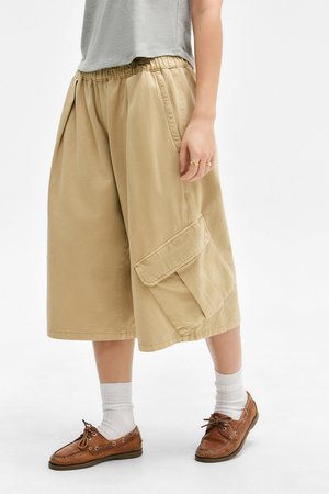 Shorts larghi color khaki con vita elasticizzata e tasca cargo laterale. Abbinati a scarpe da barca marroni e calzini bianchi alla caviglia.
