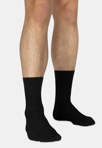 Schwarze, gerippte Crew-Socken aus weichem Material, mit einer Standardform, nahtloser Zehenpartie und bequemem Sitz am Knöchel.