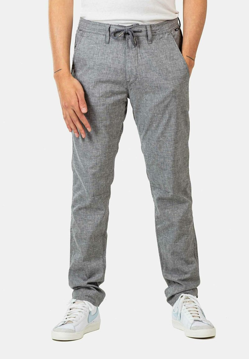 Gray, textured trousers with a drawstring waist, straight legs, and side pockets, worn with white sneakers featuring blue accents.
