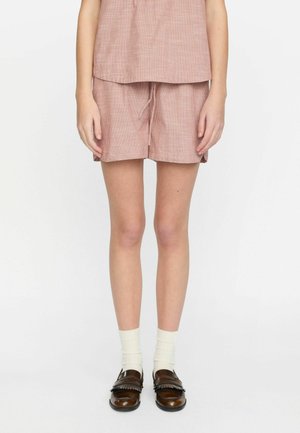 Katoenen twee-delig outfit in lichtrood met een wit geblokt patroon. Loszittende korte mouwen en shorts, gecombineerd met bruine instappers en witte sokken.