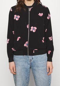 Svart bomberjacka med rosa blommönster, framdragkedja, ribbad nederkant och ärmar, långa ärmar, lättviktsmaterial.