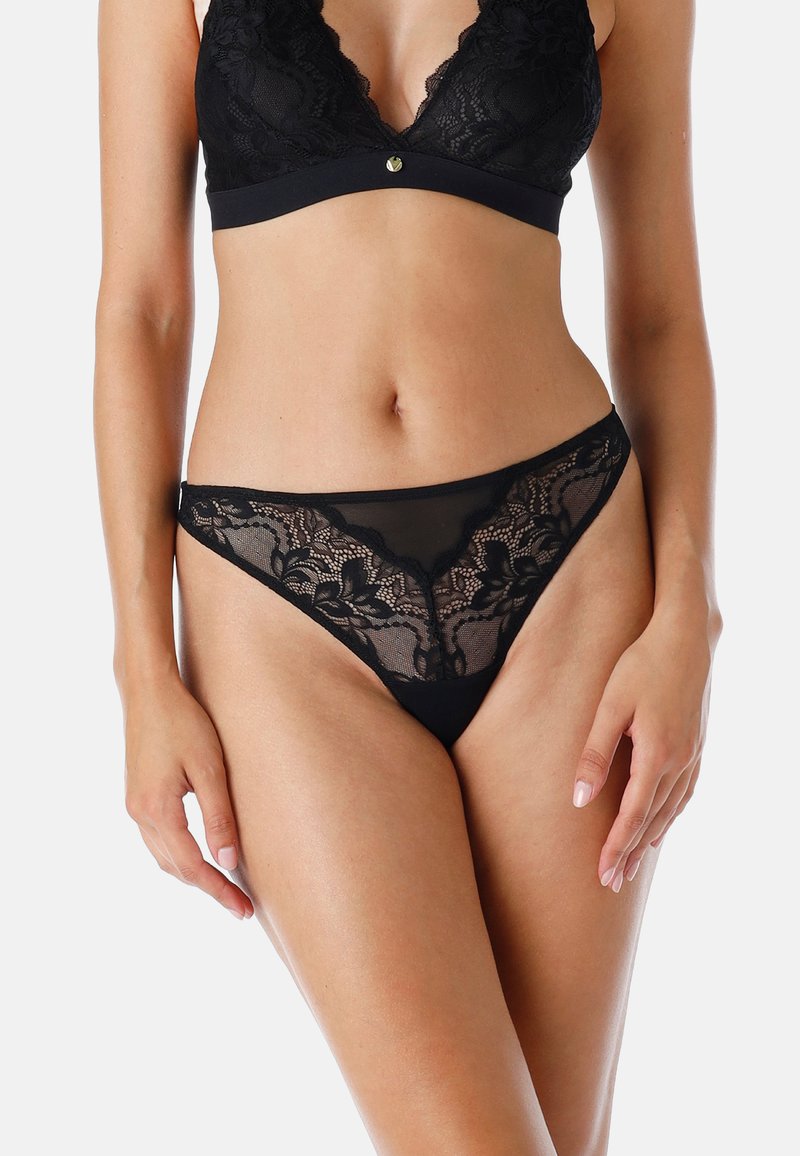 Bralette in pizzo nero con scollatura profonda a V, caratterizzata da un accento dorato nella parte anteriore. Pizzo nero coordinato con perizoma con motivo floreale e pannelli trasparenti.