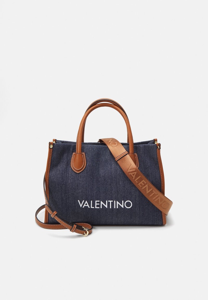 Sac tote en denim Valentino avec poignées en cuir marron, garniture et bandoulière réglable, arborant un logo Valentino en relief.