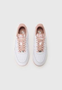 Weiße Nike Air Force 1 Sneaker mit einer weichen pinken Zunge und Schnürsenkeln. Verfügt über Perforationen an der Zehenpartie und eine glatte Ledertextur.