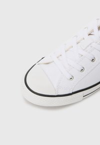 Hvite kanvas sneakers med rund tåhette, svart gummisåle og hvite lisser. Har metalløyer og teksturert sidelapp.