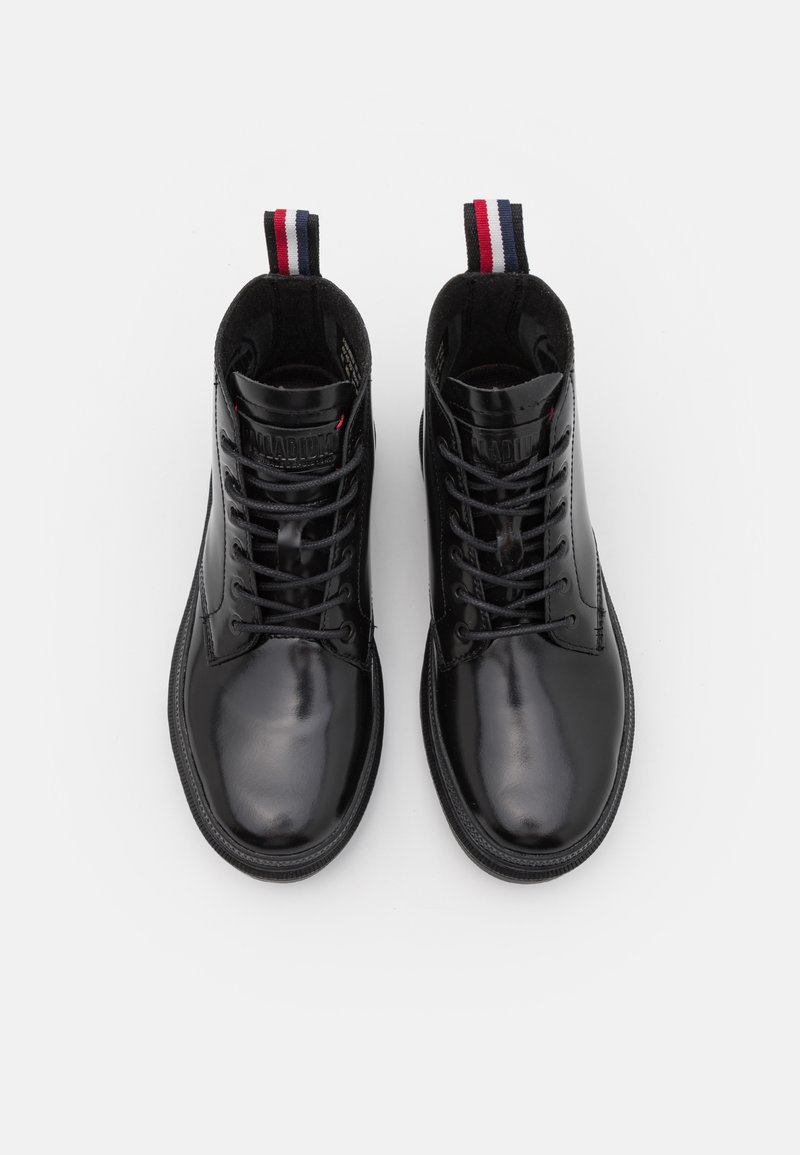 Bottes en cuir noir avec une finition brillante, des languettes rembourrées et des semelles en caoutchouc texturé. Présente une tirette rayée aux couleurs rouge, blanc et bleu.