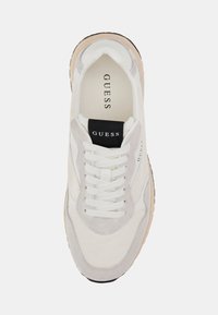 Witte sneaker met lichtgrijze suède accenten, opvallende veters en een getextureerde zool. Voorzien van een zwart logolabel op de tong.