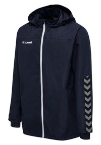 Granatowa kurtka przeciwdeszczowa z kapturem, białym zamkiem błyskawicznym, odblaskowymi paskami w jodełkę na prawym rękawie oraz logo hummel na piersi.