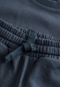 Tissu de sport bleu foncé montrant une surface texturée avec une taille élastique et un détail de cordon noué.