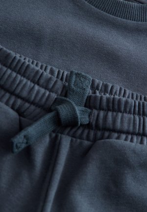 Dunkelblauer Sportstoff mit strukturierter Oberfläche, elastischem Bund und einer verknoteten Kordelzug-Details.