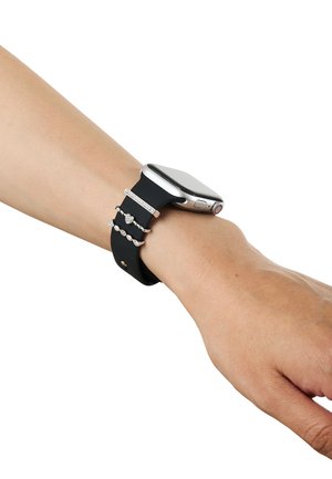 Handgelenk mit schwarzer Smartwatch und drei silbernen Ringen am Uhrenarmband vor weißem Hintergrund.