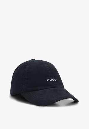 Dark blue corduroy baseball cap with a curved visor and white embroidered "HUGO" logo on the front. Textured fabric, adjustable strap at back.