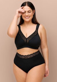 Completo reggiseno e slip a vita alta con pizzo nero. Il reggiseno presenta un design a scollo a V con spalline larghe e tessuto morbido, mentre gli slip hanno dettagli in pizzo.
