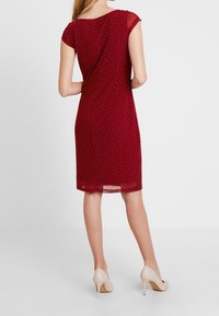 Rode jurk met polka dot patroon, korte mouwen, aansluitend ontwerp en een lengte tot op de knie. Gemaakt van lichtgewicht stof, met een lichte glans.