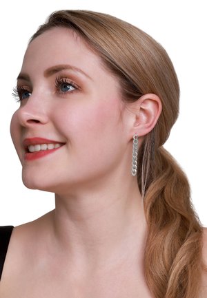 Zilveren oorbellen in kettingstijl met een delicate schakeling, die iets onder de oorlel hangen. Gladde textuur en reflecterende afwerking.
