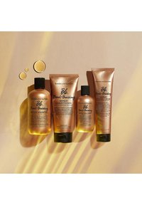 Bumble and bumble Bond-Building hårvårdsset: amberfärgade flaskor och tuber, olika storlekar, gyllene vätska, matta och blanka texturer, svarta och gyllene accenter.