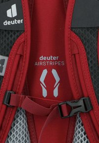 Sangle de sac à dos rouge et noire avec texture en maille, dotée d'une boucle en plastique et de la marque "deuter AIRSTRIPES" en gris.