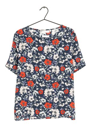 Marineblaue kurzärmelige Bluse mit rot-weiß-lila Blumenmuster, die auf einem schwarzen Bügel vor weißem Hintergrund hängt.