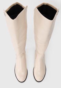 Knæhøje, beige syntetiske læderstøvler med en glat tekstur, rund tå, minimale detaljer og en tætsiddende silhuet.