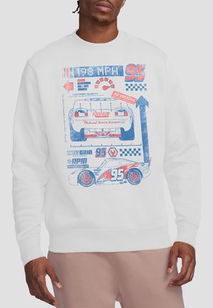Man wearing white sweatshirt with red and blue vintage racing car and speedometer graphic featuring number 95 and racing symbols.