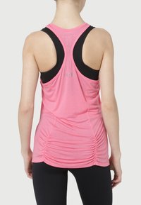 Różowy sportowy top z czarnymi akcentami, z tyłem typu racerback i marszczoną fakturą z tyłu. Lekki materiał zapewniający komfort.