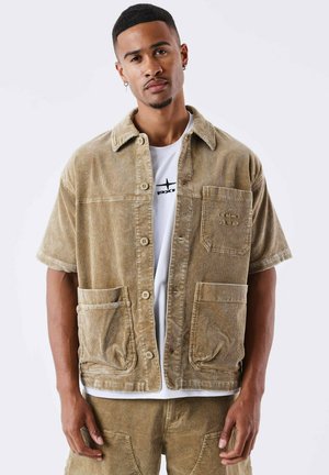 Khaki corduroy shirt jacket with short sleeves, chest pocket, and two front pockets. Features button closure and textured fabric.