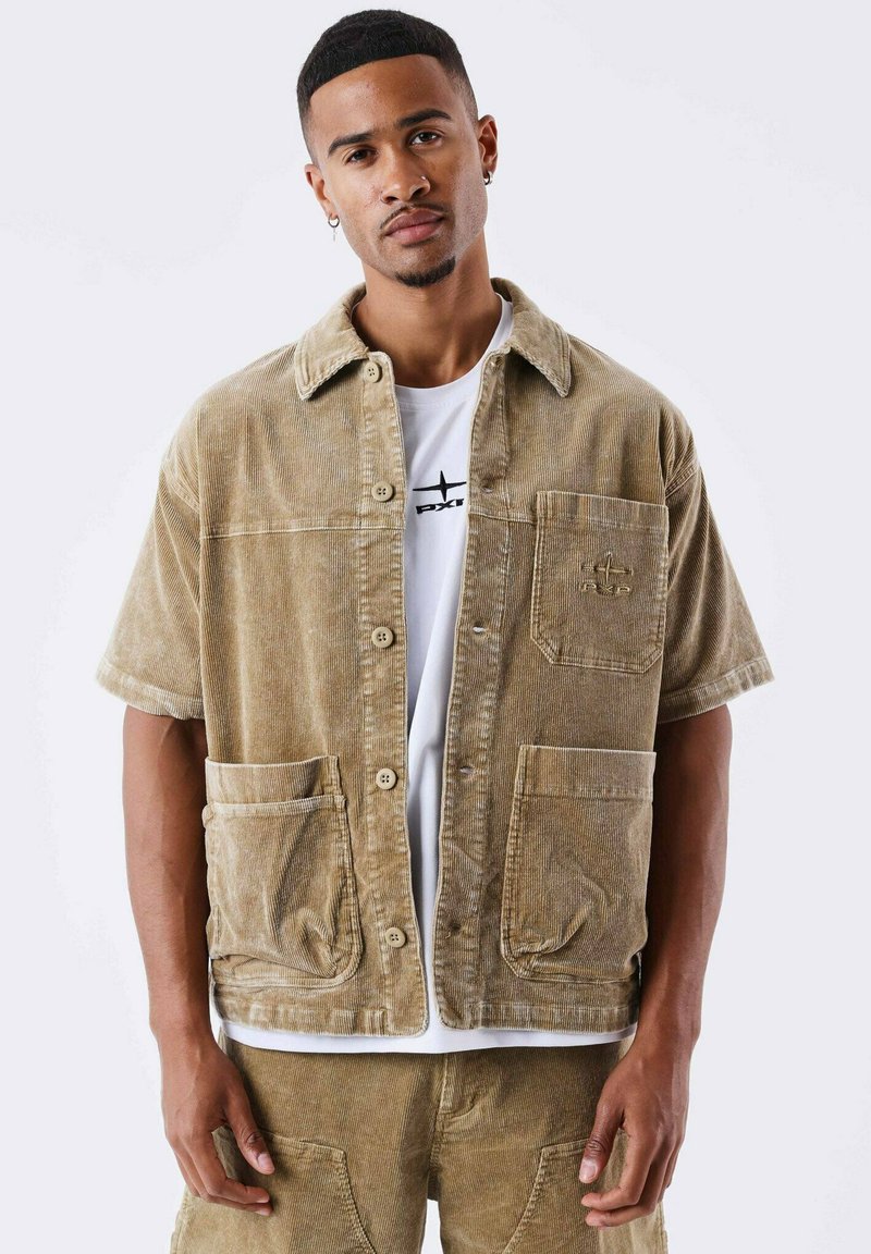 Veste chemise en velours côtelé khaki à manches courtes, avec une poche poitrine et deux poches avant. Elle est dotée d'une fermeture à boutons et d'un tissu texturé.