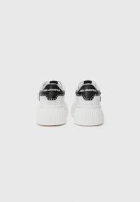 Hvite sneakers med en ribbet såle, med svarte detaljer på hælen med "KARL LAGERFELD"-merket. Glatt materiale, avrundet form.