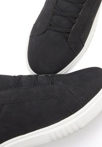 Schwarze Sneakers mit einer glatten Wildleder-Oberfläche, ausgestattet mit schwarzen Schnürsenkeln, einer weißen Gummisohle und einer abgerundeten Zehenpartie.