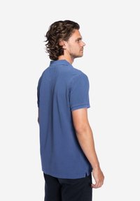 Poloshirt in zachtblauwe katoen met een knoopsluiting van twee knopen, korte mouwen en een rugpand detail. Zijsplitsen aan de zoom verhogen het comfort.