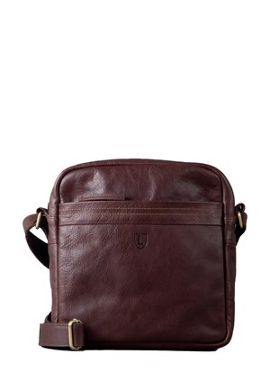 Braune Leder-Crossbody-Tasche mit weicher Textur, einem Reißverschluss-Vordertasche und verstellbarem Trageriemen. Enthält ein dezentes, geprägtes Logo auf der Vorderseite.
