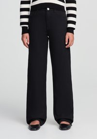 Czarne szerokie spodnie w stylu denimowym o gładkiej fakturze. Posiadają przednie kieszenie oraz srebrny guzik jako akcent.