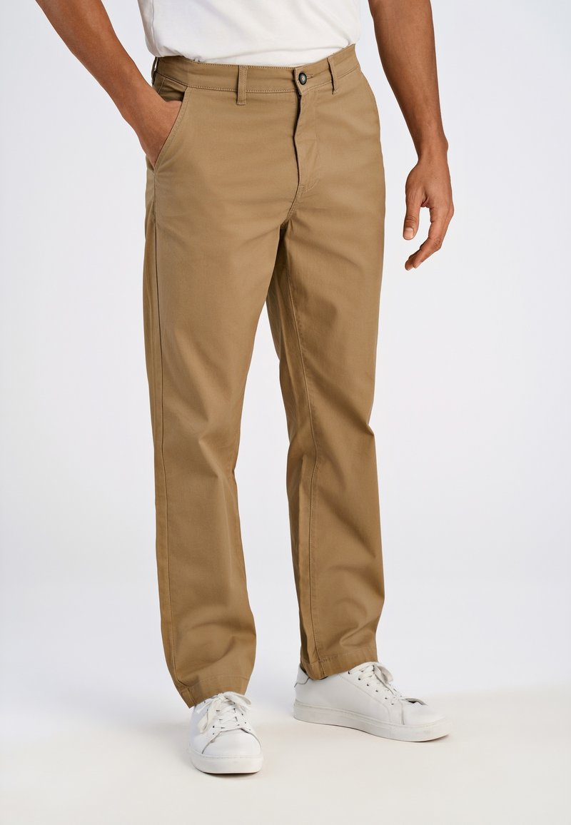 Beige katoenen chino's met een rechte pasvorm, voorzien van voorzakken, een knoopsluiting en een gladde textuur, gecombineerd met witte sneakers.