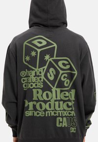 Zwarte hoodie met grote groene grafische print op de achterkant met dobbelsteenontwerp, merktekst en verschillende zinnen. Zacht, textuurstof.