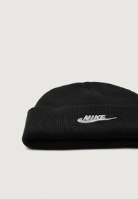 Černá pletená čepice s žebrovanou strukturou a ohrnutým lemem, na přední straně s vyšitým bílým logem Nike.