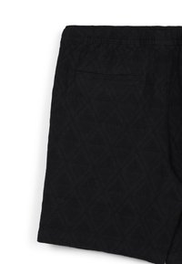 Shorts noirs en tissu texturé avec un motif en losanges. Dotés d'une poche arrière et d'une taille élastique.