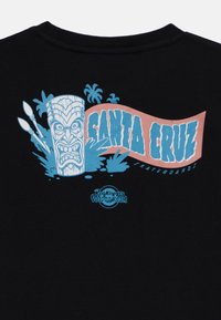 Czarna koszulka z grafiką niebieskiej tiki maski z palmami, różową wstęgą z napisem "SANTA CRUZ" oraz tekstem "Roskopp's Voodooroom".