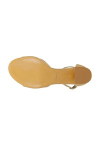 Braune, strukturierte Gummisohle eines High-Heel-Sandalen, ausgestattet mit einem beigen Riemendesign und metallischen Details am Knöchel.