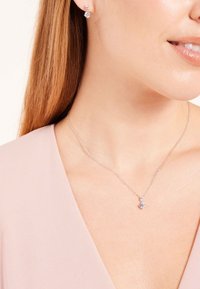 Silberne Kettenhalskette mit einem einzelnen klaren Anh�änger und dazu passenden Ohrsteckern. Glatte Textur und modernes Design mit schimmernden Akzenten.