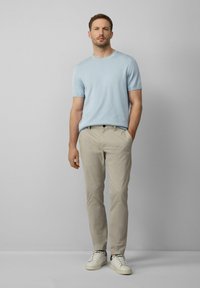Lichtblauw korte mouwen gebreid shirt gecombineerd met beige chino's en witte sneakers, met een relaxte pasvorm en eenvoudig ontwerp. Casual outfit.