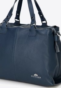 Borsa a mano in pelle blu navy con doppi manici, chiusura con zip e dettaglio del logo argentato. Texture liscia con cuciture visibili.