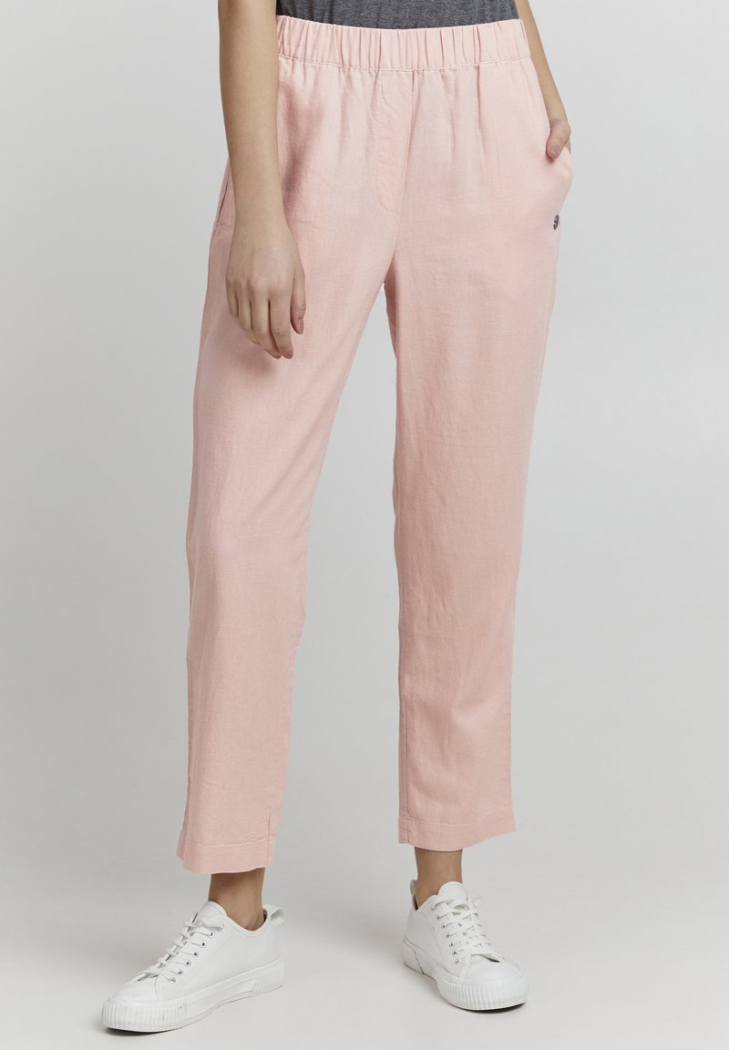 Lys rosa linbukser med elastisk midje, sidelommer og rett snitt, kombinert med hvite sneakers for et avslappet utseende.