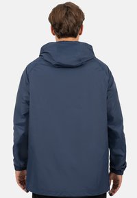 Marineblauwe windbreakerjack met capuchon, elastische manchetten en een ontspannen pasvorm. Glad, lichtgewicht materiaal, geen zichtbare patronen of accenten.